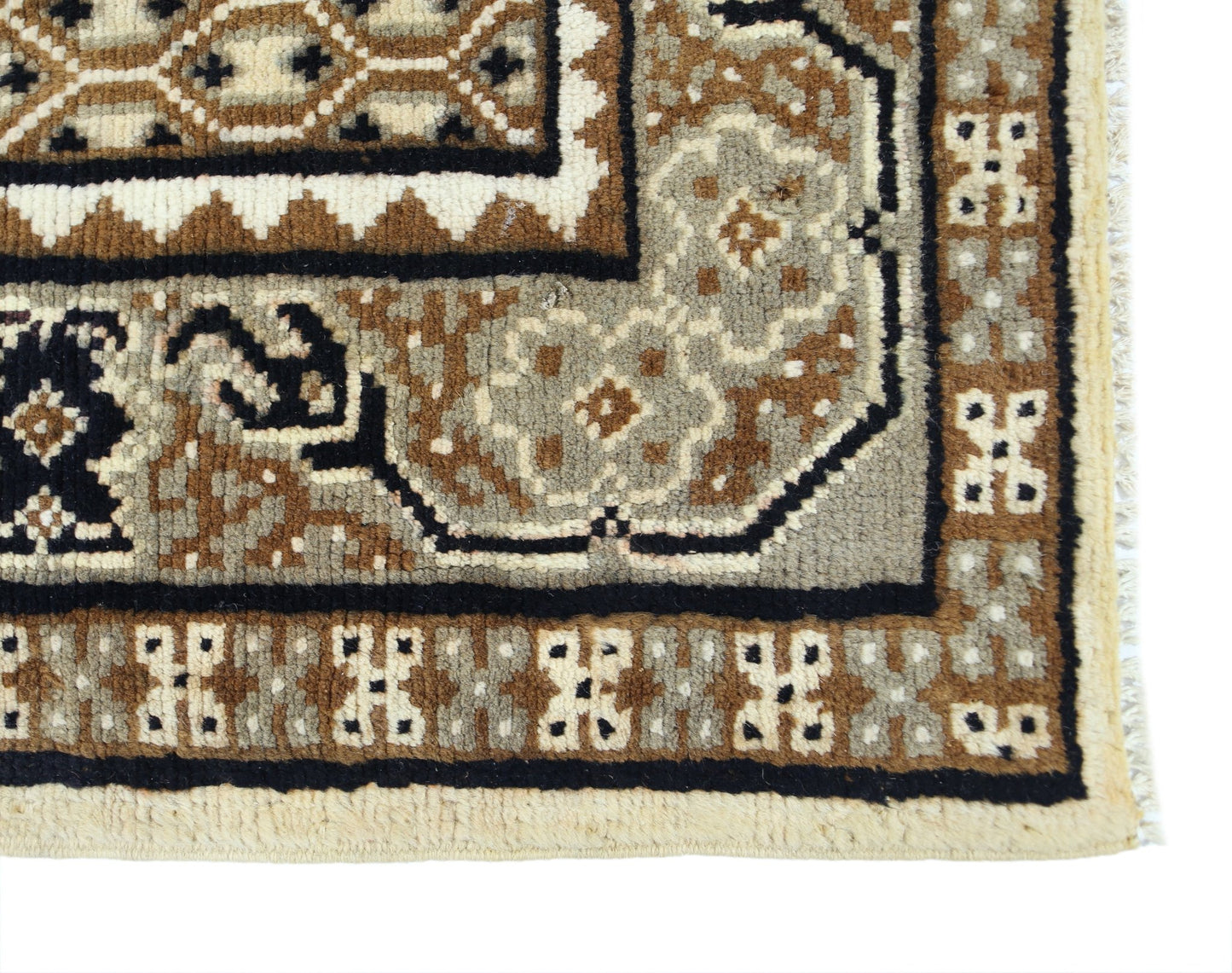 A close-up of a handwoven Afghan rug featuring geometric tribal patterns in brown and cream wool.