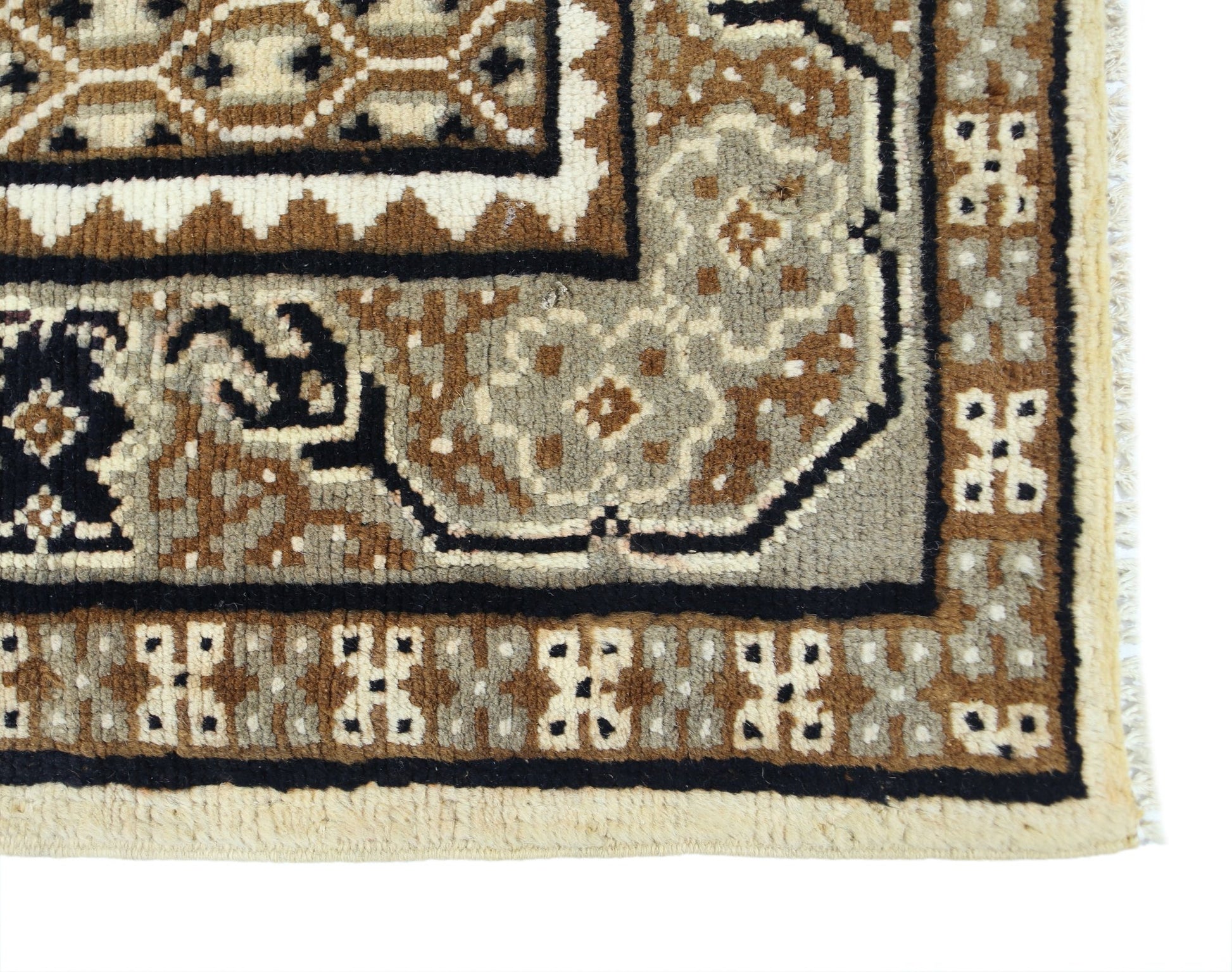 A close-up of a handwoven Afghan rug featuring geometric tribal patterns in brown and cream wool.