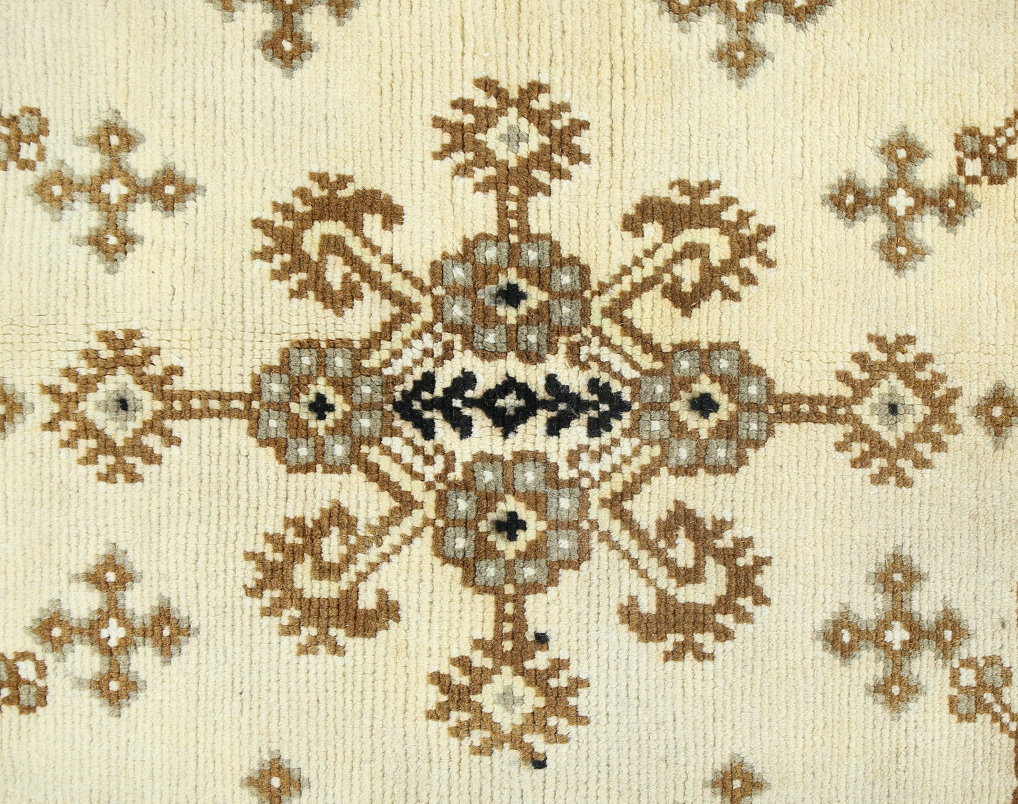A vintage handwoven Afghan rug featuring a repeating geometric floral pattern in brown and cream.