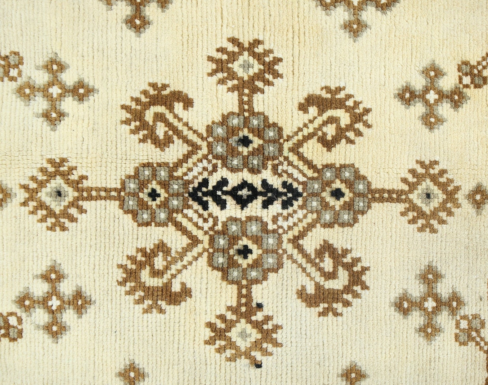 A vintage handwoven Afghan rug featuring a repeating geometric floral pattern in brown and cream.