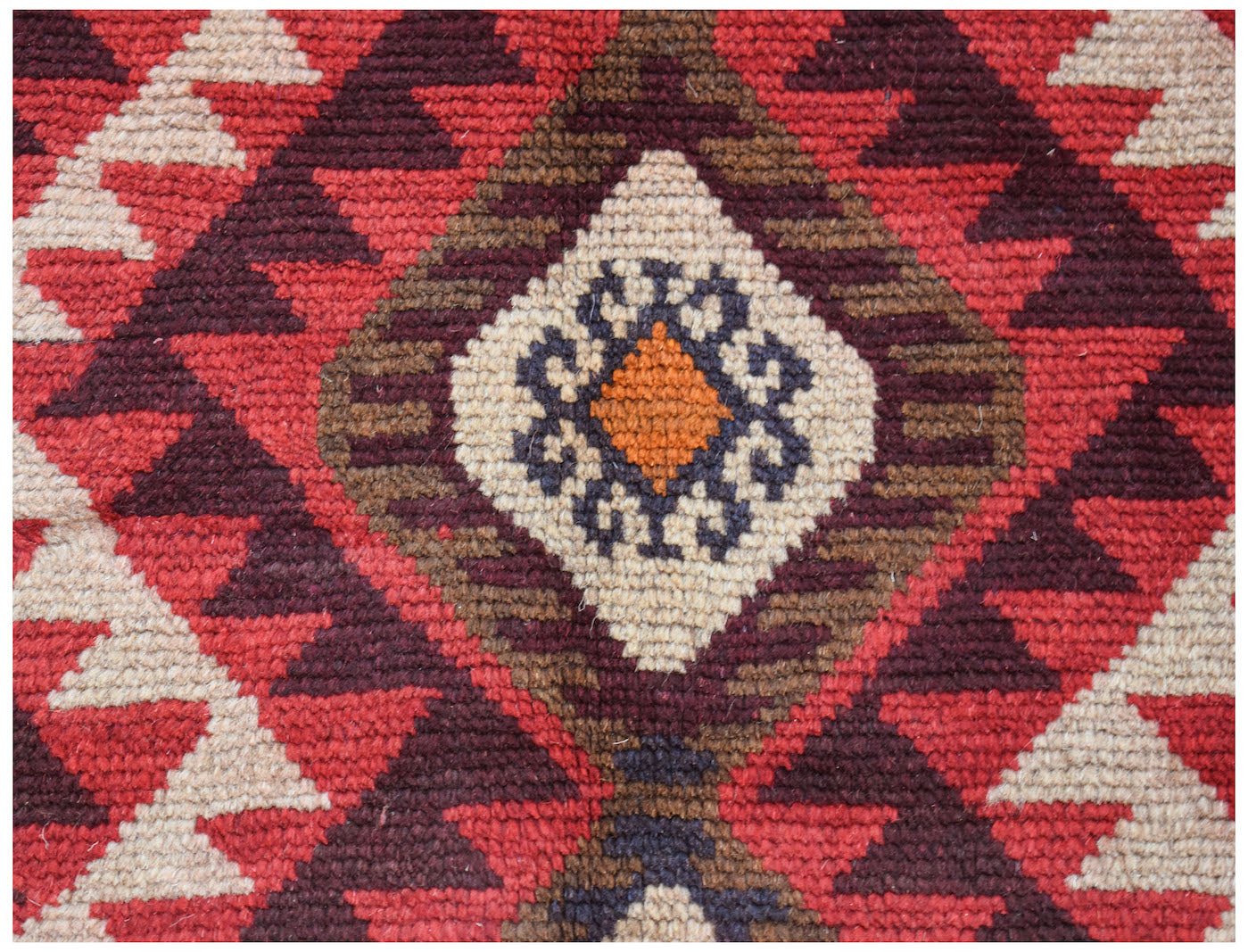 A handmade Afghan Pashm rug featuring a geometric diamond pattern in red, brown, and ivory wool.