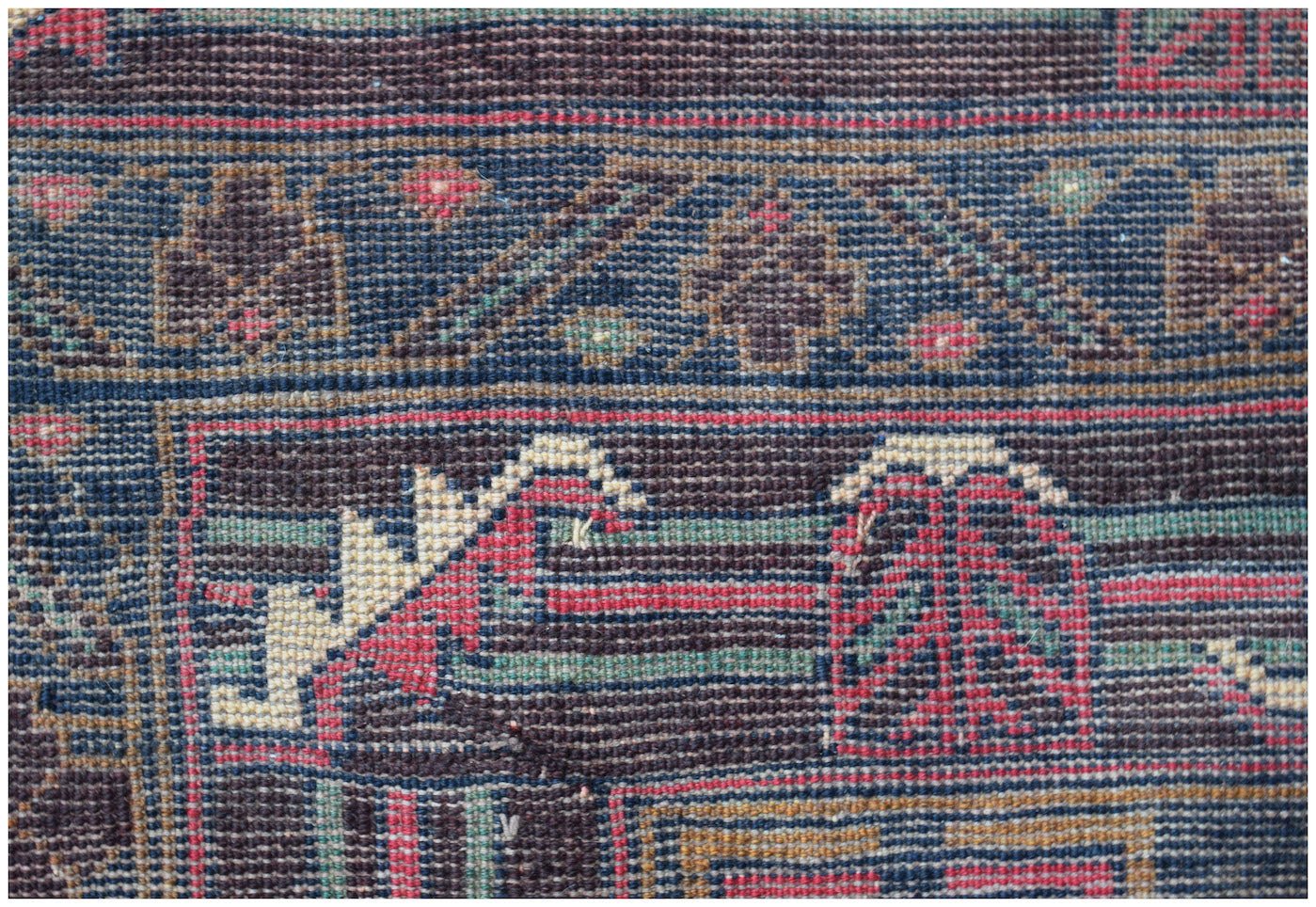 A handmade Afghan Pashm rug featuring a dark blue and brown geometric tribal pattern.