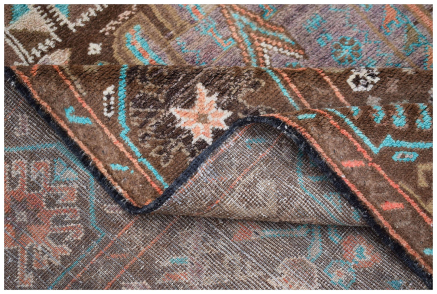 A handmade Afghan Pashm rug featuring a tribal pattern in shades of brown, blue, and orange.