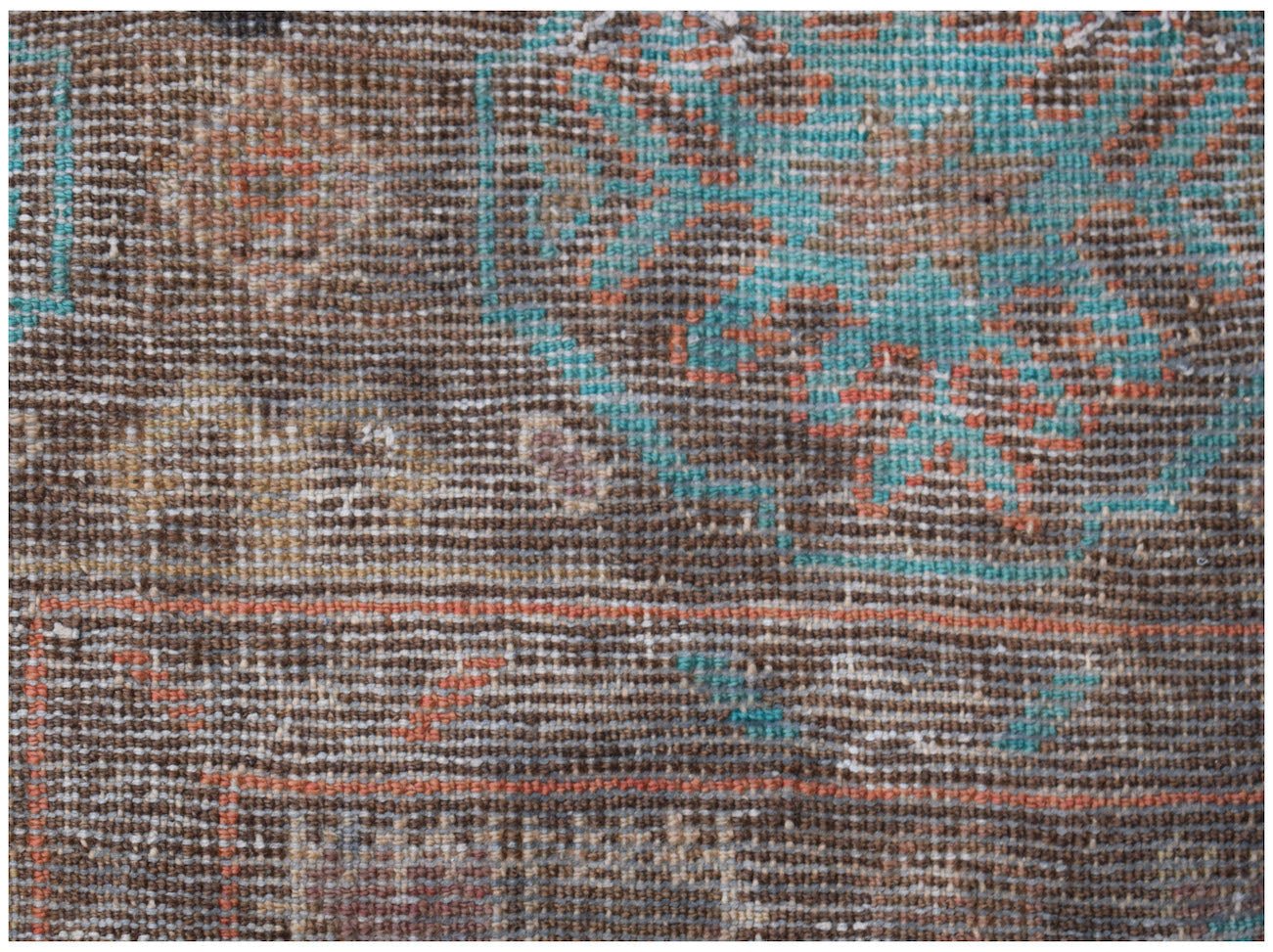A close-up of a handmade Afghan Pashm rug featuring geometric patterns in brown, blue, and orange.