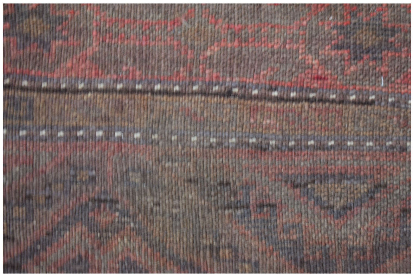 A close-up of a handmade Afghan Pashm rug featuring dark red and brown geometric tribal patterns.