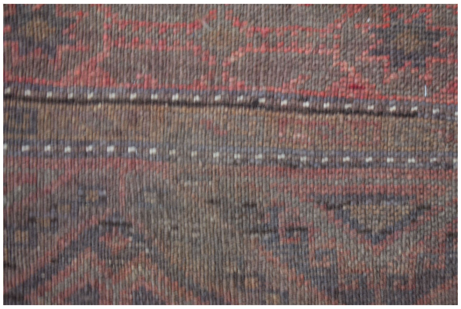 A close-up of a handmade Afghan Pashm rug featuring dark red and brown geometric tribal patterns.