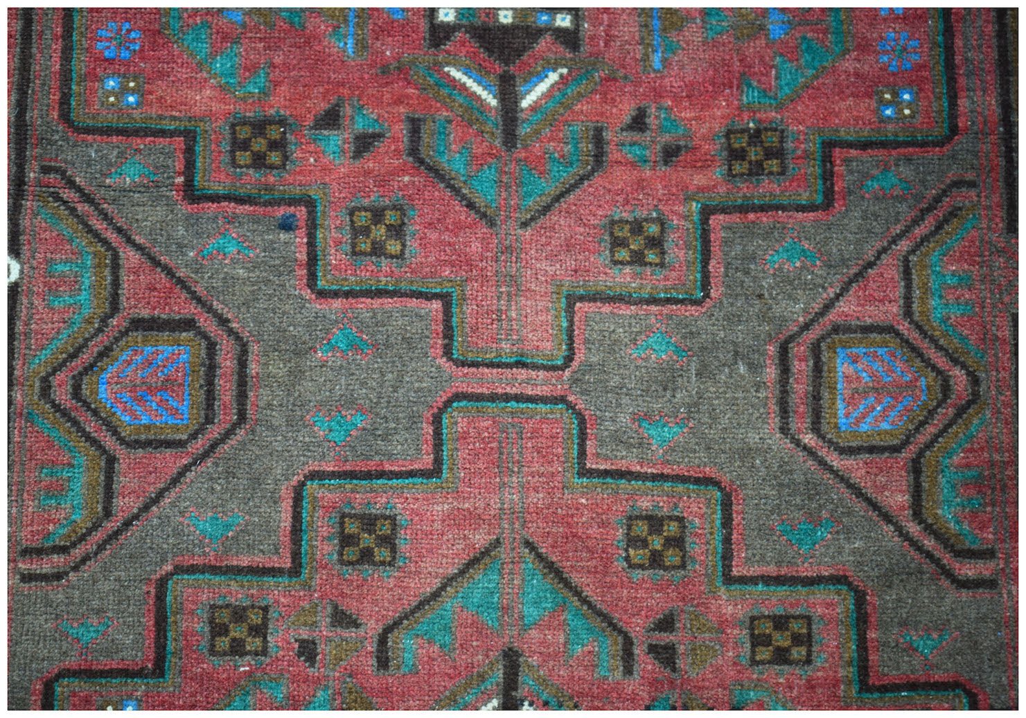 Handmade Afghan Pashm rug featuring a geometric tribal pattern in shades of red, brown, and blue.