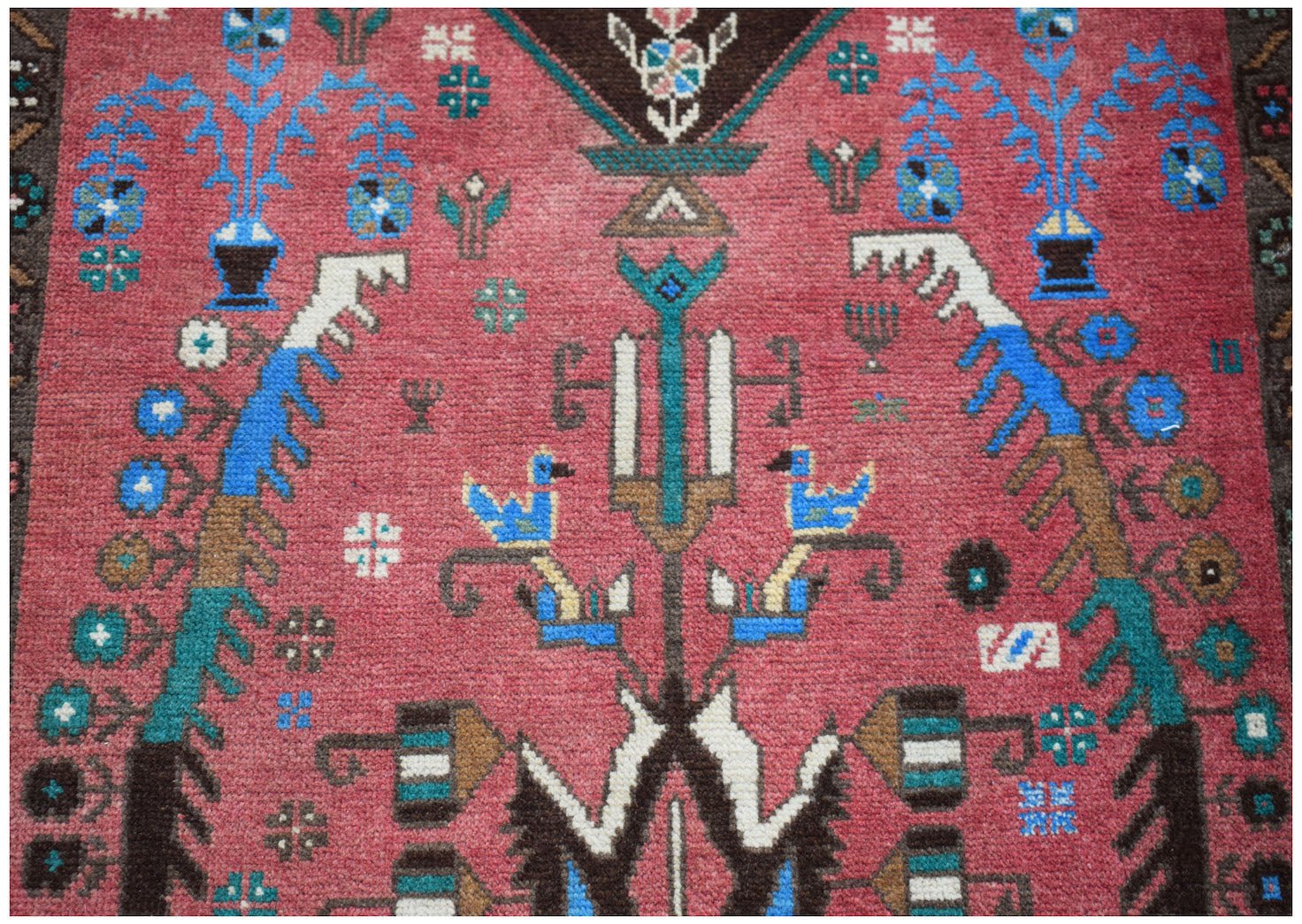 Handmade Afghan Pashm rug featuring a traditional tribal design in red, blue, and brown wool.