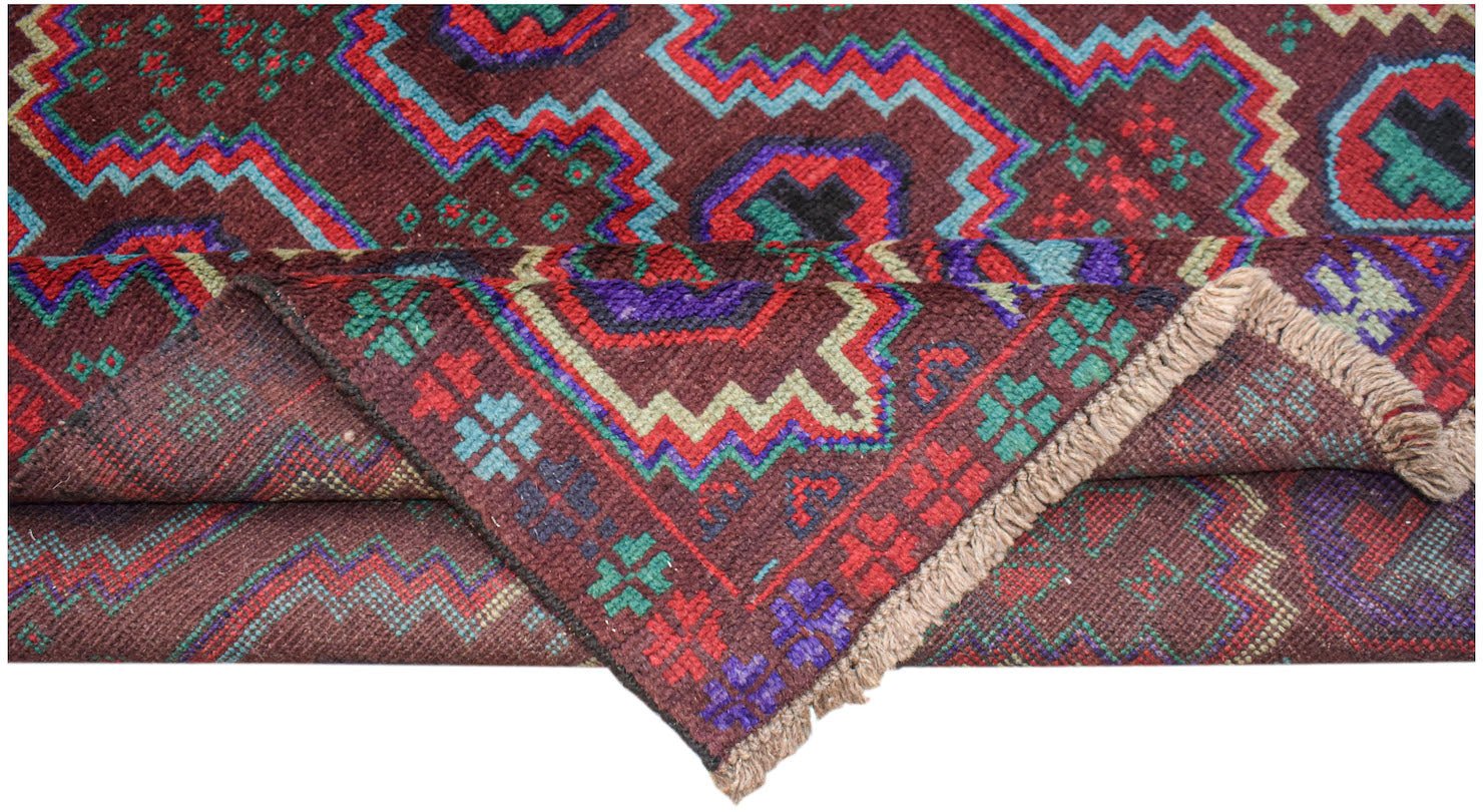 A handmade Afghan Pashm rug featuring a geometric tribal pattern in deep red, blue, and brown.