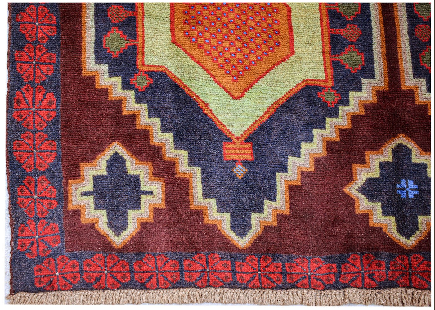 Handmade Afghan Pashm rug featuring a geometric pattern in dark red, blue, and lime green.