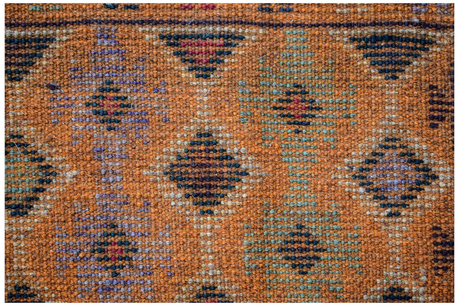 Handmade Afghan wool rug featuring a geometric diamond pattern in earthy orange and dark tones.