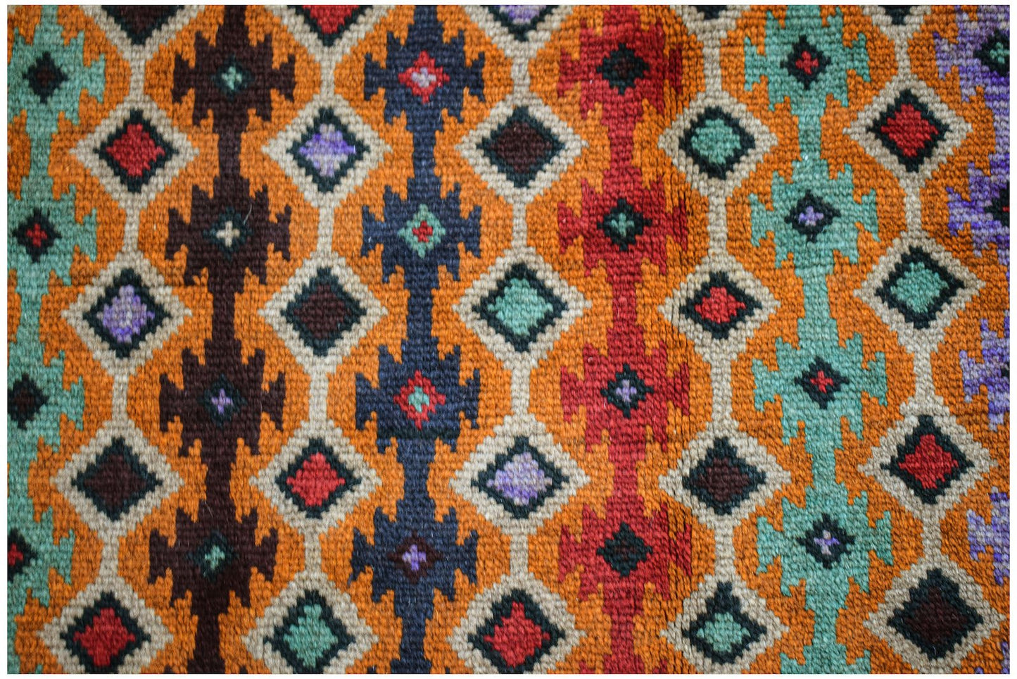 Handmade Afghan Pashm rug featuring a geometric diamond pattern in vibrant red, blue, and orange.