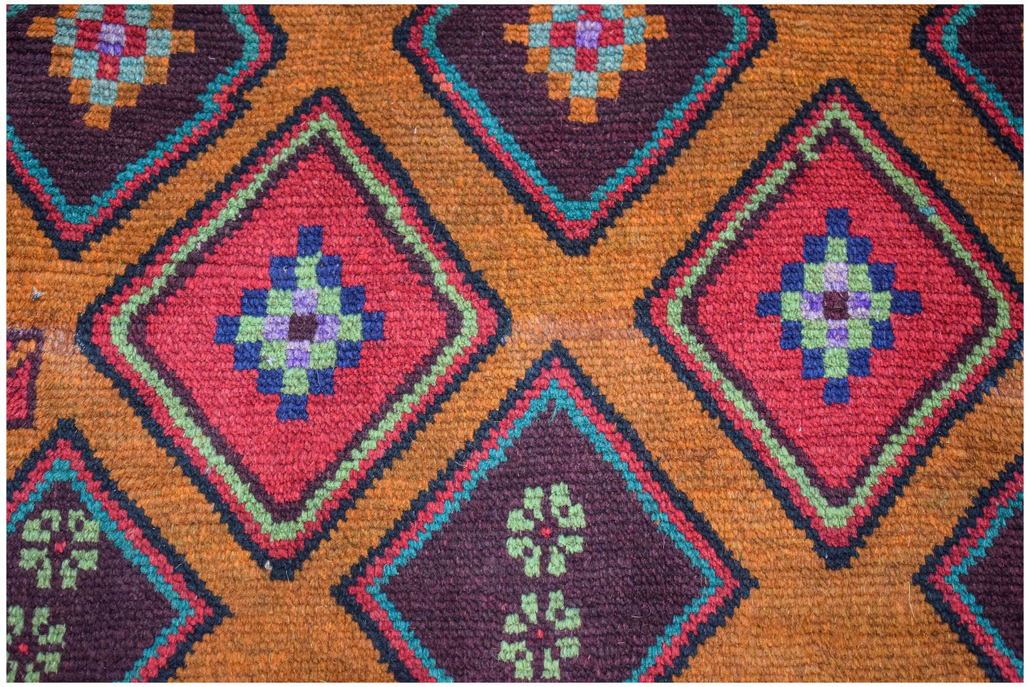Handmade Afghan Pashm rug featuring a geometric diamond pattern in red, brown, and blue wool.