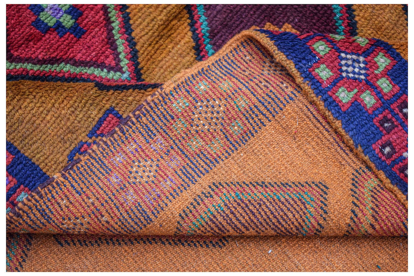 A handmade Afghan Pashm rug featuring a geometric tribal pattern in deep red, blue, and brown tones.