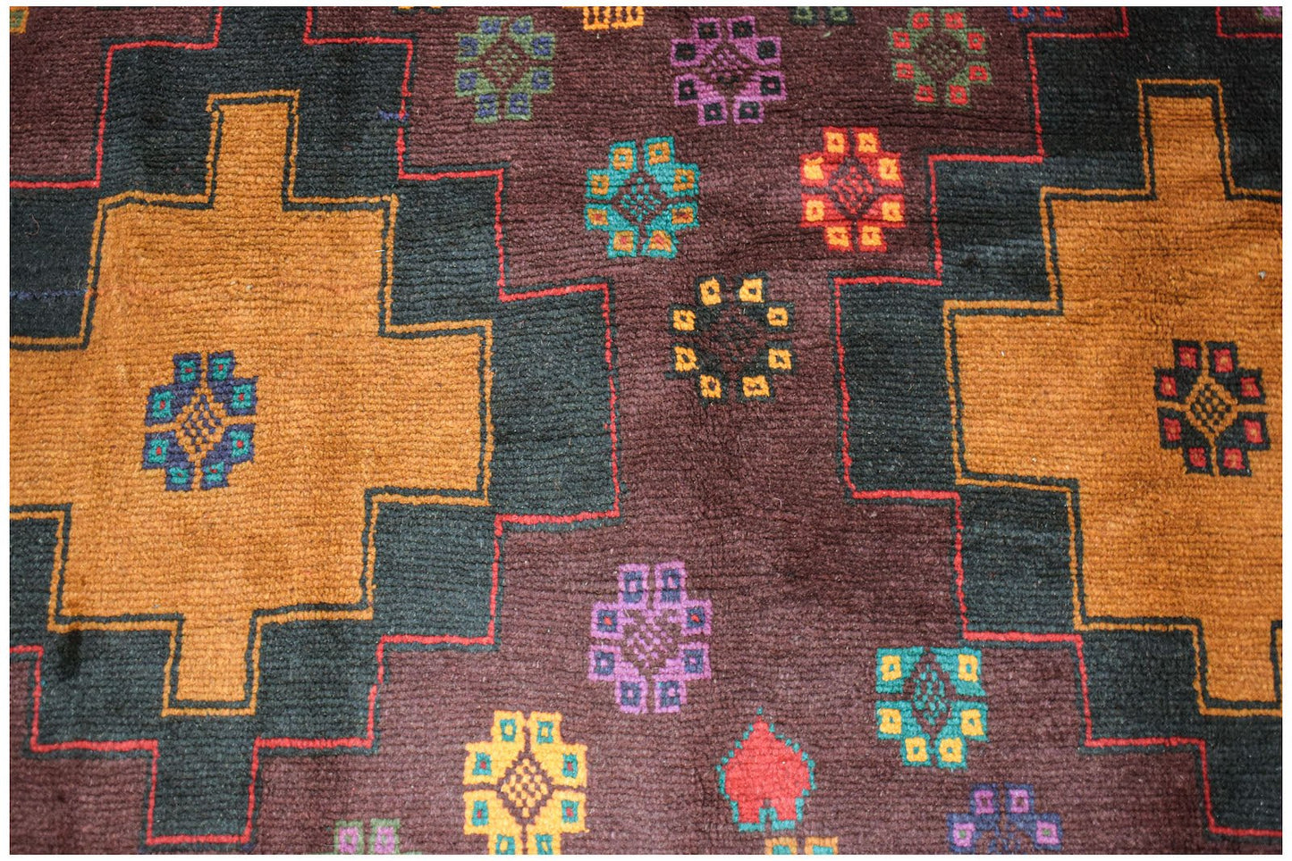 Handmade Afghan Pashm rug featuring geometric patterns in orange, black, and deep brown wool.