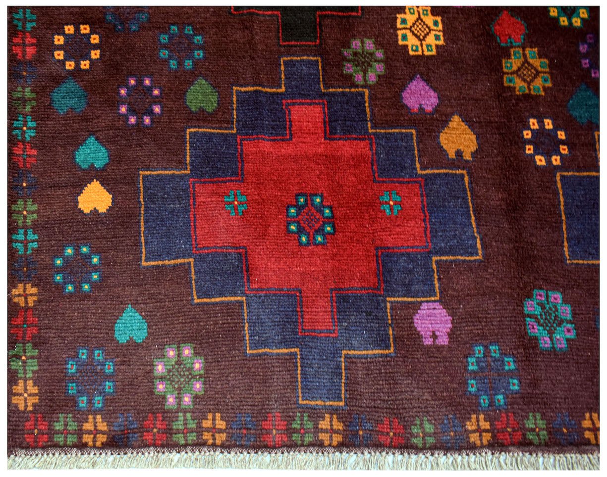 Handmade Afghan Pashm rug featuring a geometric red and blue medallion on a dark brown field.