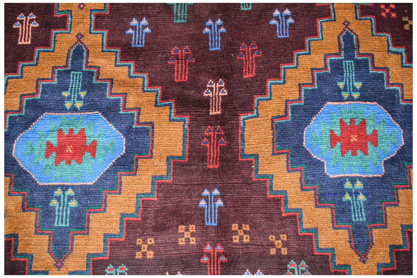 Handmade Afghan Pashm rug featuring geometric diamond patterns in dark red, blue, and brown wool.