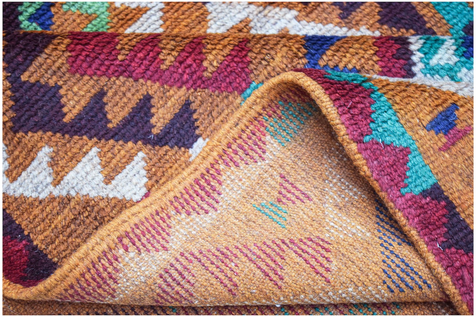 Afghan Pashm rug with geometric patterns in red, brown, and blue.