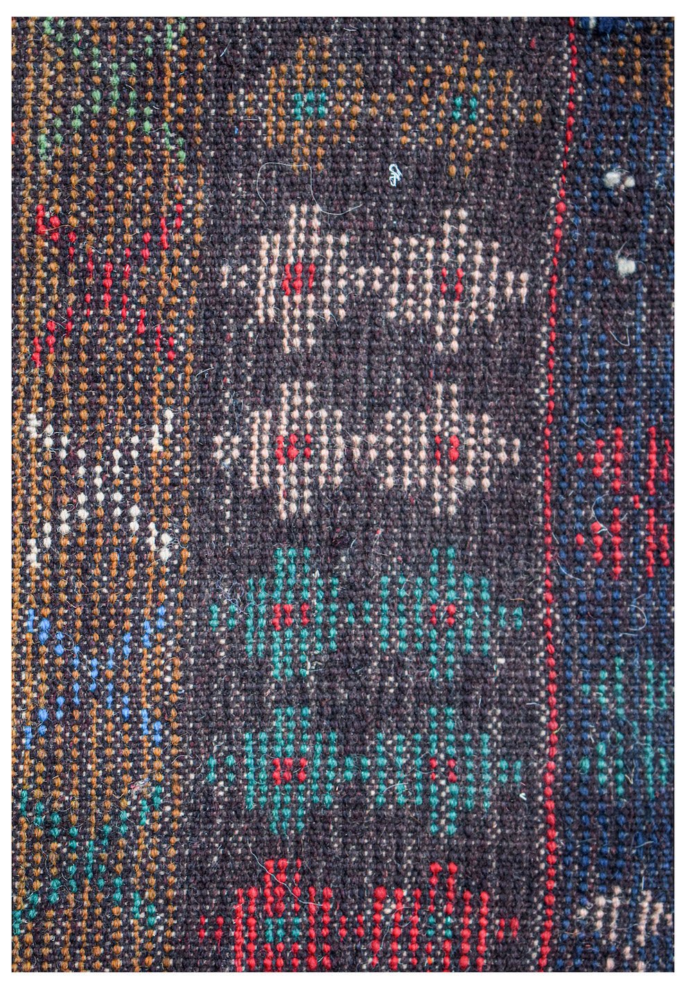 Handmade Afghan Pashm rug featuring geometric diamond patterns in red, blue, and ivory on dark wool.
