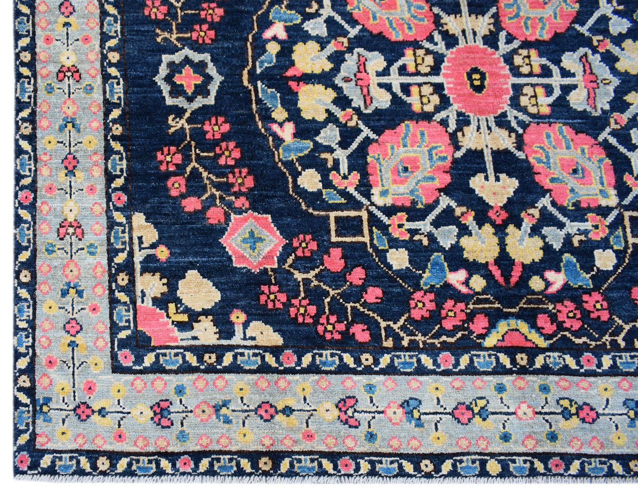 Handmade Afghan Pashm rug featuring a dark blue field with a floral medallion and patterned border.