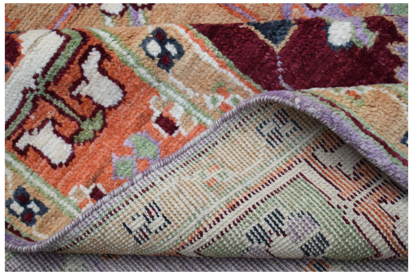 A corner of a handmade Afghan wool rug is folded back to reveal its intricate woven backing.