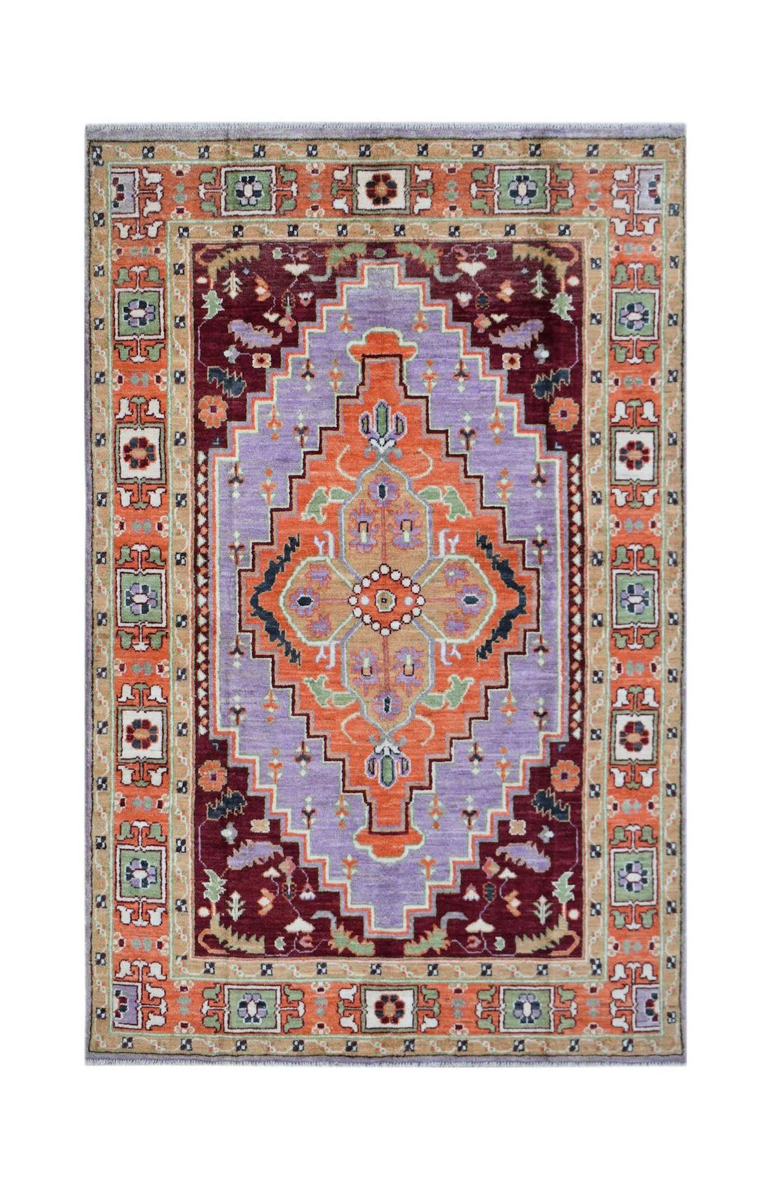 Handmade Afghan wool rug featuring a central geometric medallion in orange and purple tones.