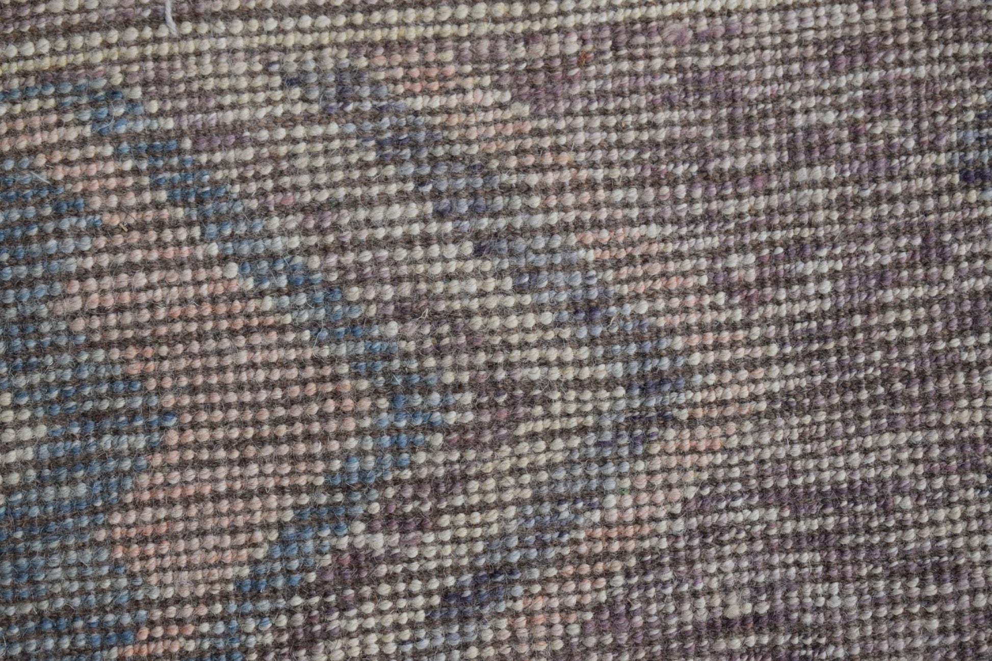 A close-up view of a handmade Afghan Pashm rug featuring a textured, woven wool pattern.