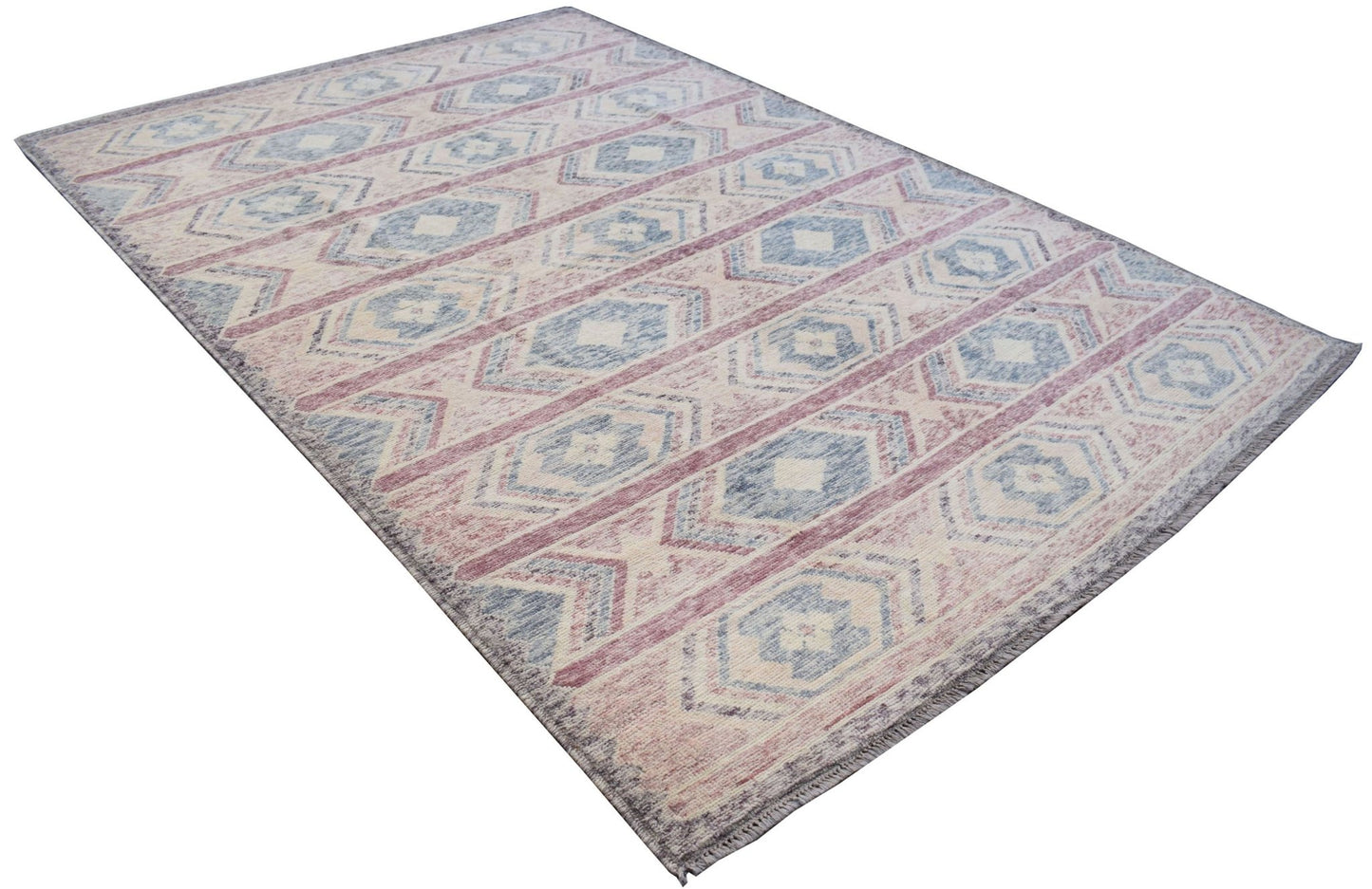 A handmade Afghan wool rug featuring a geometric tribal pattern in shades of blue, pink, and cream.