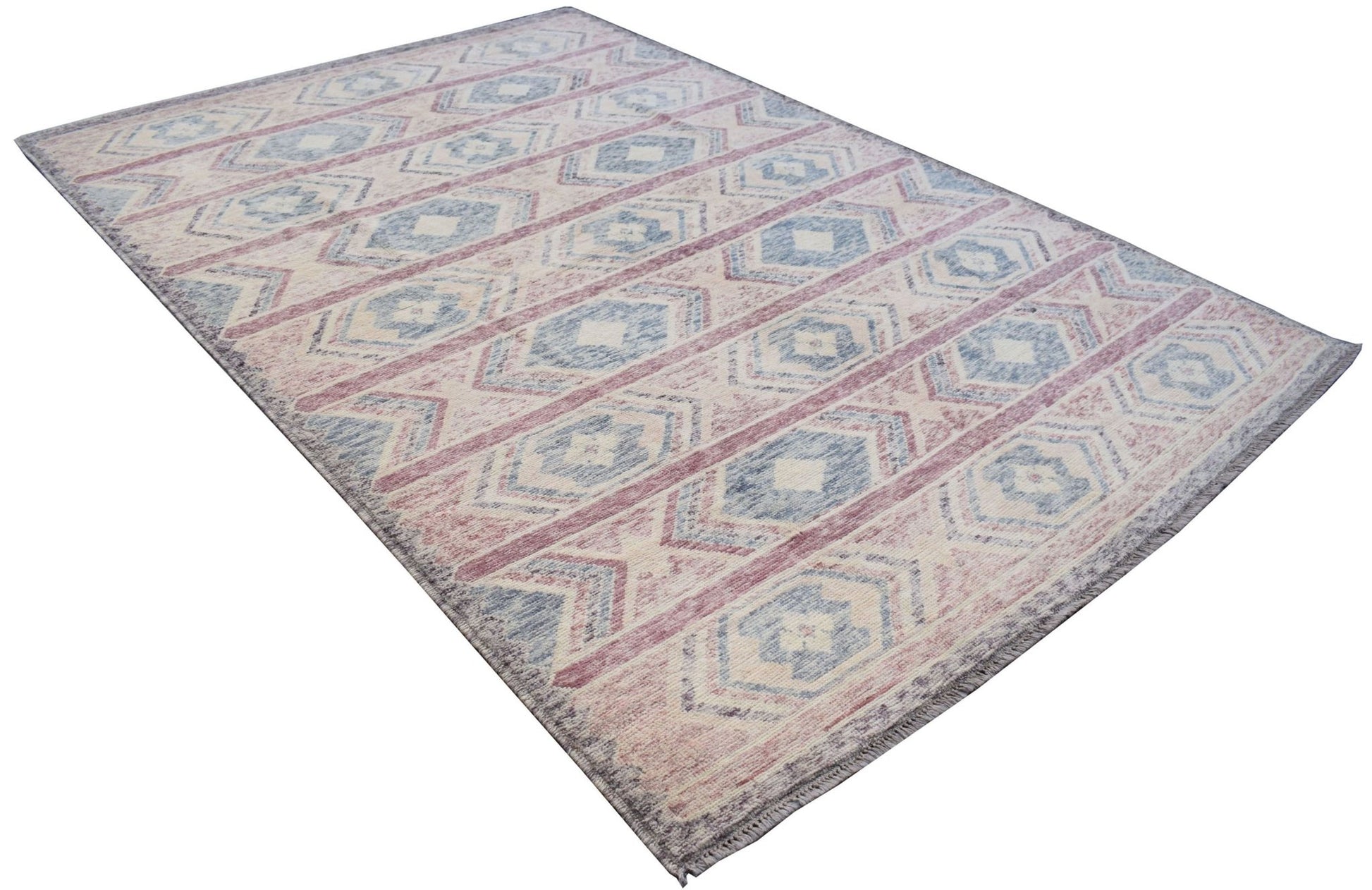 A handmade Afghan wool rug featuring a geometric tribal pattern in shades of blue, pink, and cream.
