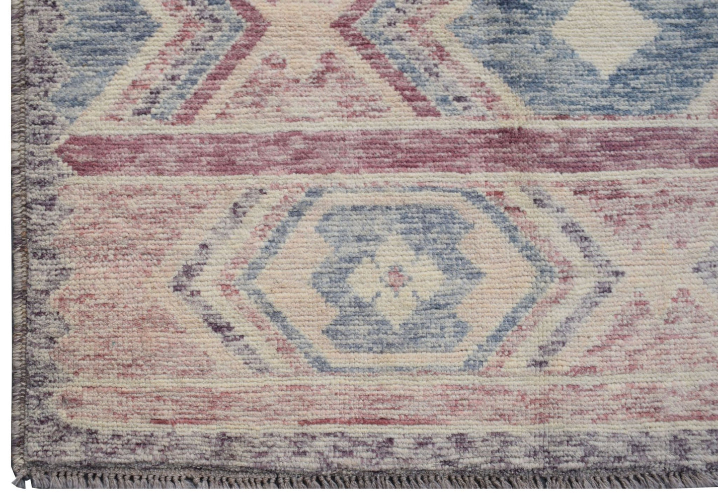 A handmade Afghan wool rug featuring a geometric tribal pattern in shades of blue, pink, and cream.