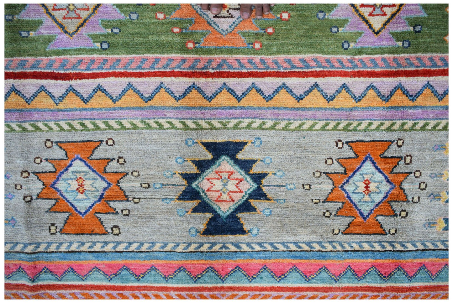 Handmade Afghan wool rug featuring colorful geometric tribal patterns on a light gray background.