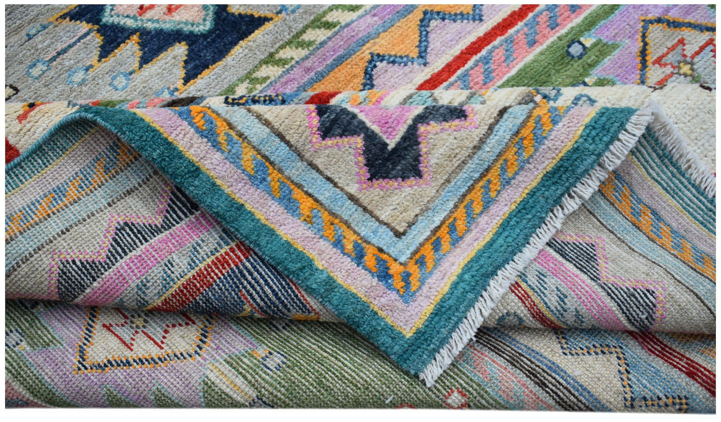 A folded Afghan Pashm wool rug featuring a vibrant, multi-colored geometric tribal pattern.