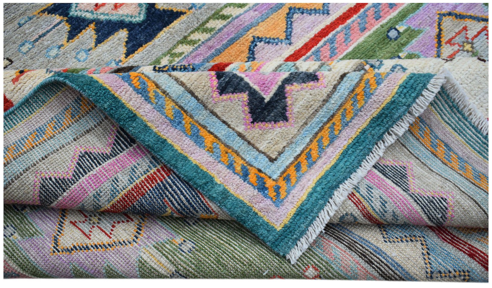 A folded Afghan Pashm wool rug featuring a vibrant, multi-colored geometric tribal pattern.