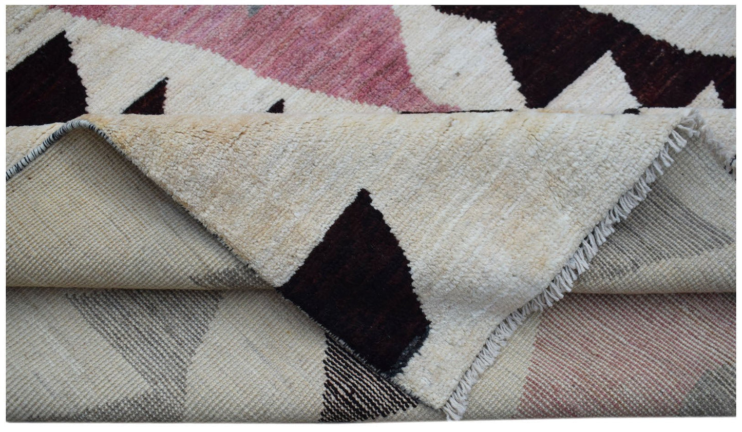 A handmade Afghan wool rug featuring a geometric pattern in pink, dark brown, and cream.
