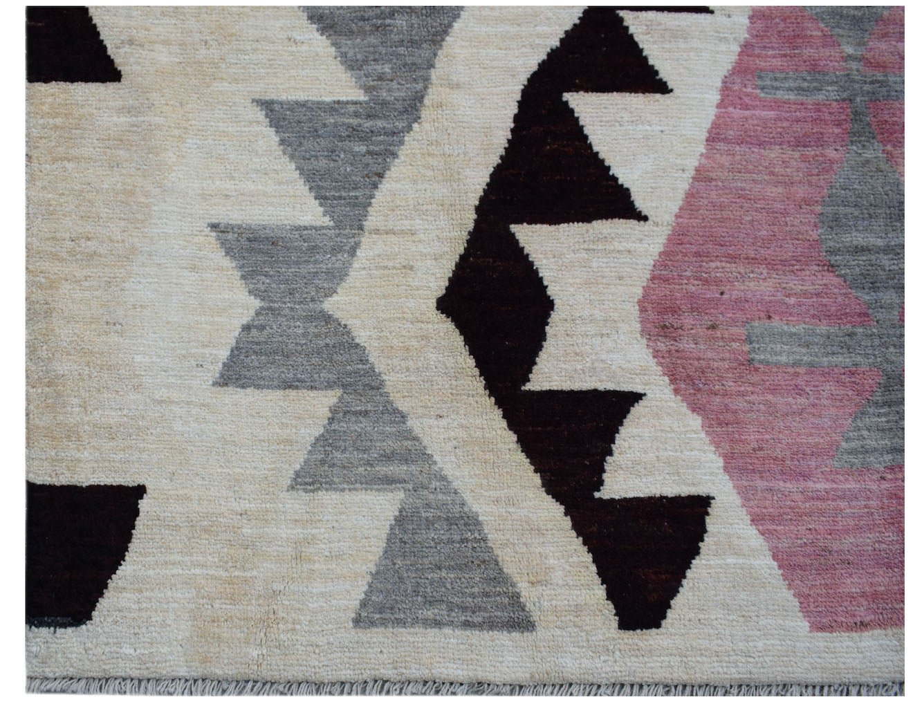 A handmade Afghan wool rug featuring a geometric tribal pattern in cream, grey, black, and pink.