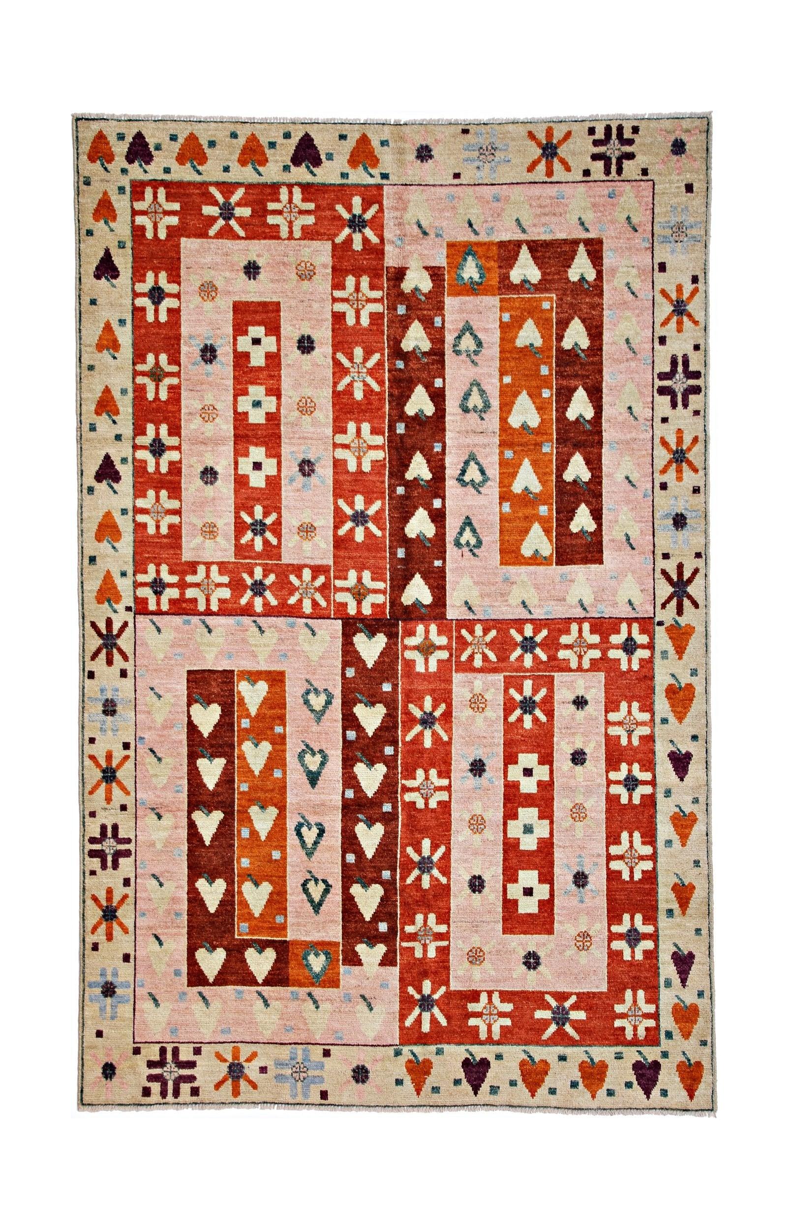 Handmade wool rug featuring a geometric patchwork design in shades of pink, orange, and red.