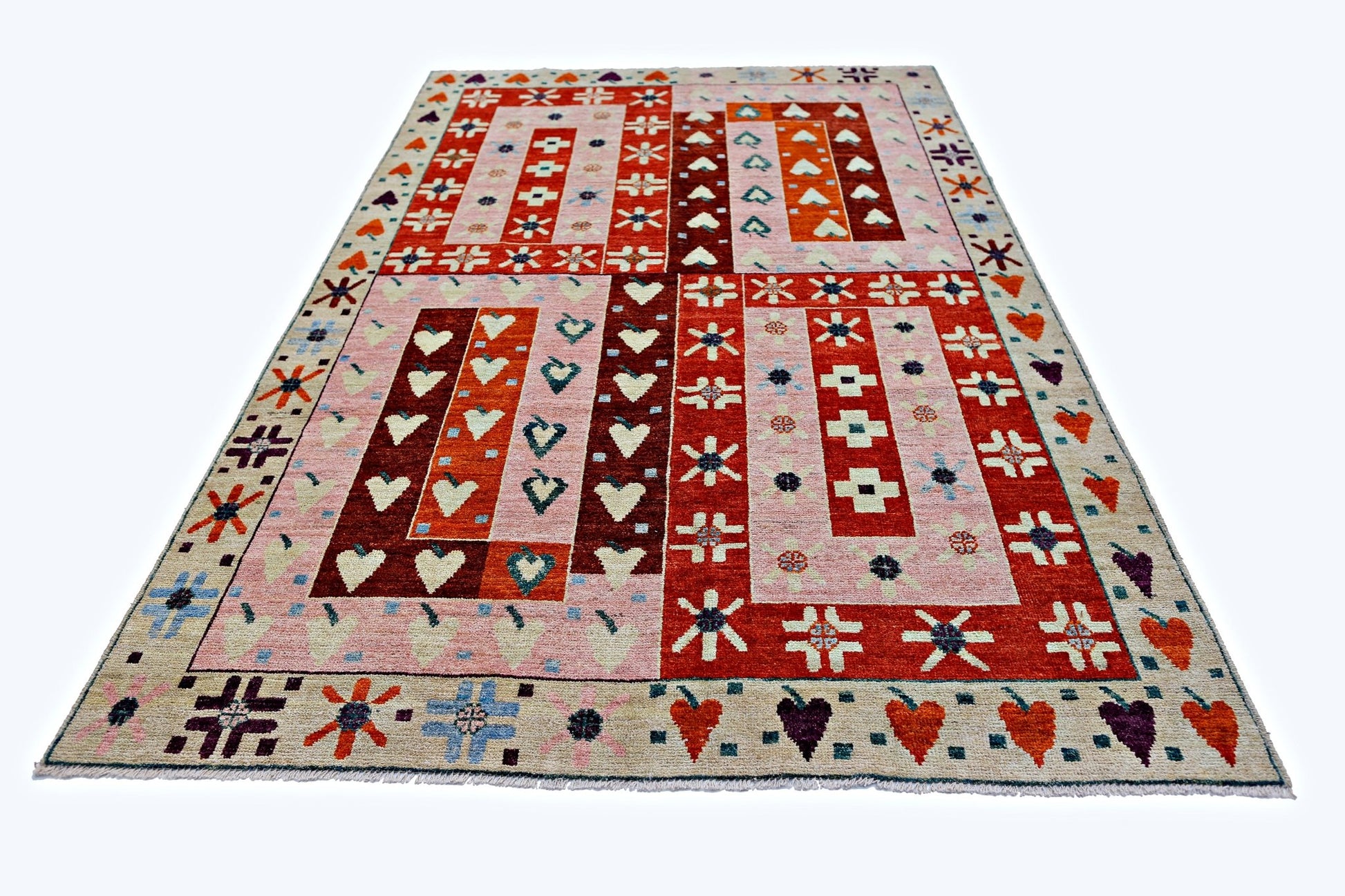 A handmade wool rug from Afghanistan featuring a geometric pattern of hearts and stars in red and pink.