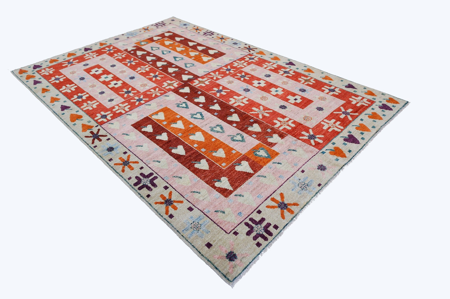 A handmade wool rug from Afghanistan featuring a geometric pattern in red, orange, and cream.