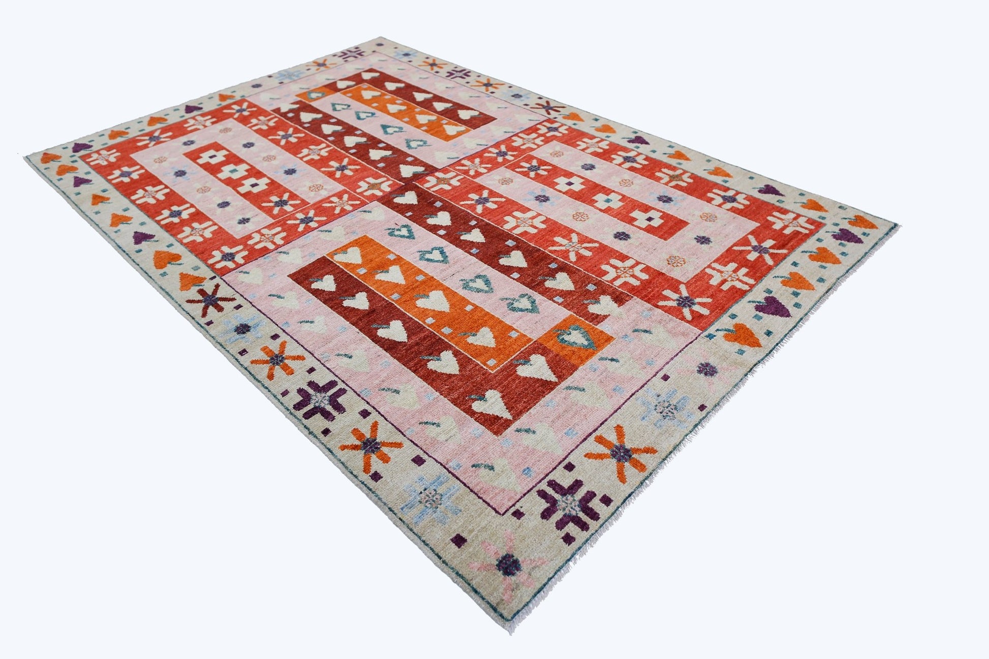 A handmade wool rug from Afghanistan featuring a geometric pattern in red, orange, and cream.