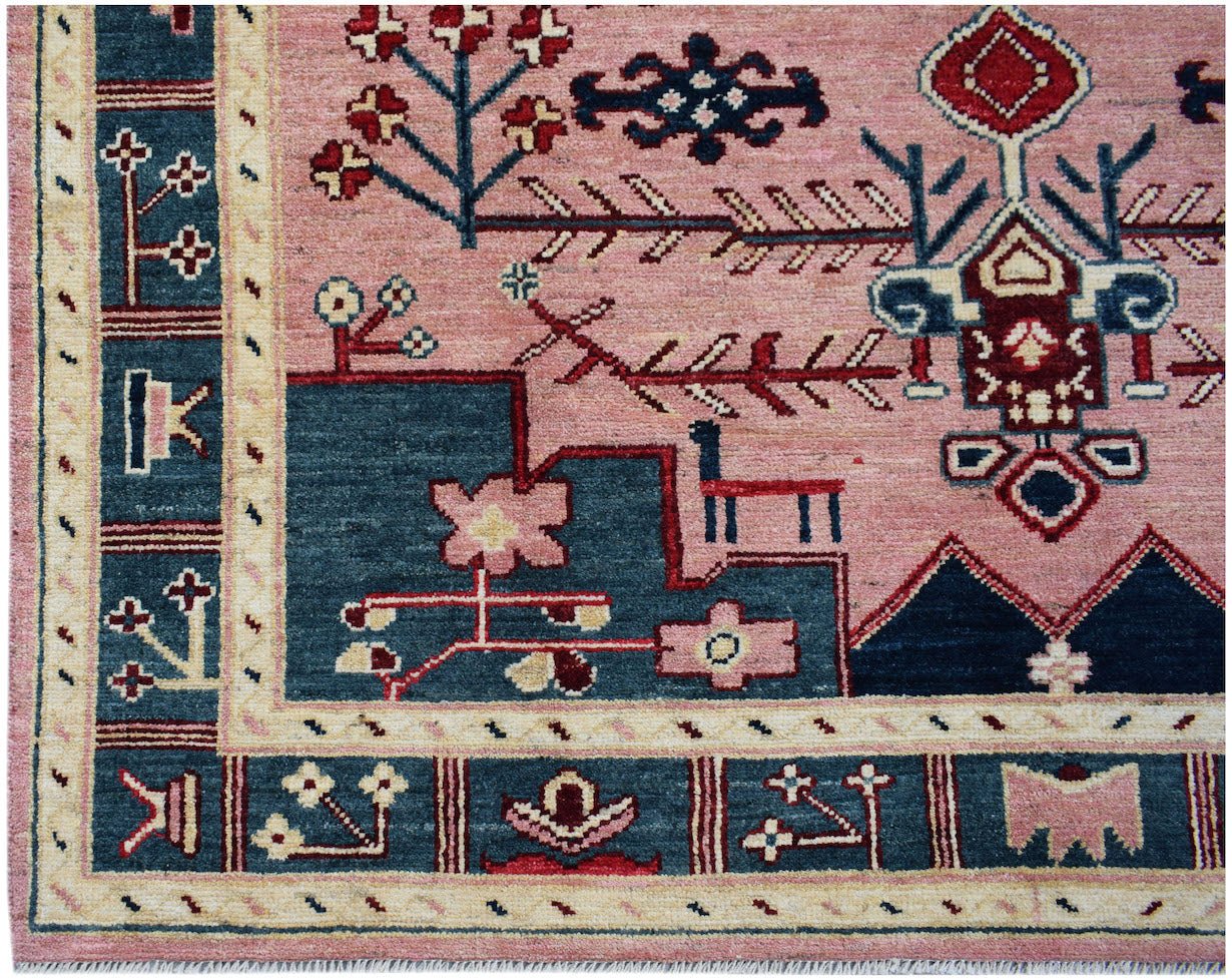 Handmade Afghan wool rug featuring a pink field with blue geometric floral and animal motifs.