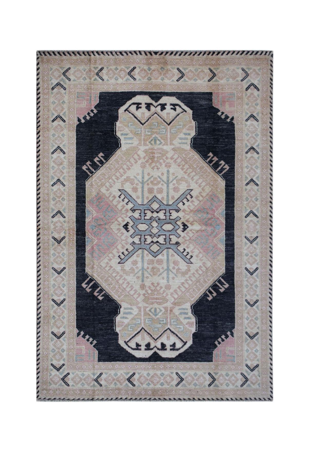 A handmade wool rug featuring a dark central medallion with geometric patterns in pink and blue.