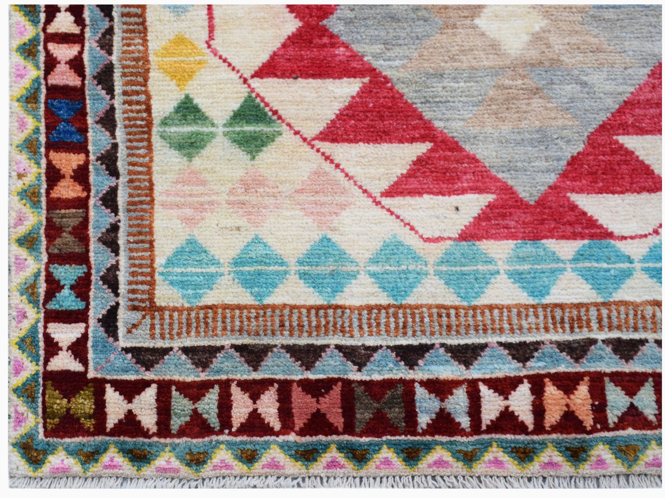 A handmade Afghan wool rug featuring a geometric tribal pattern with colorful diamond motifs.