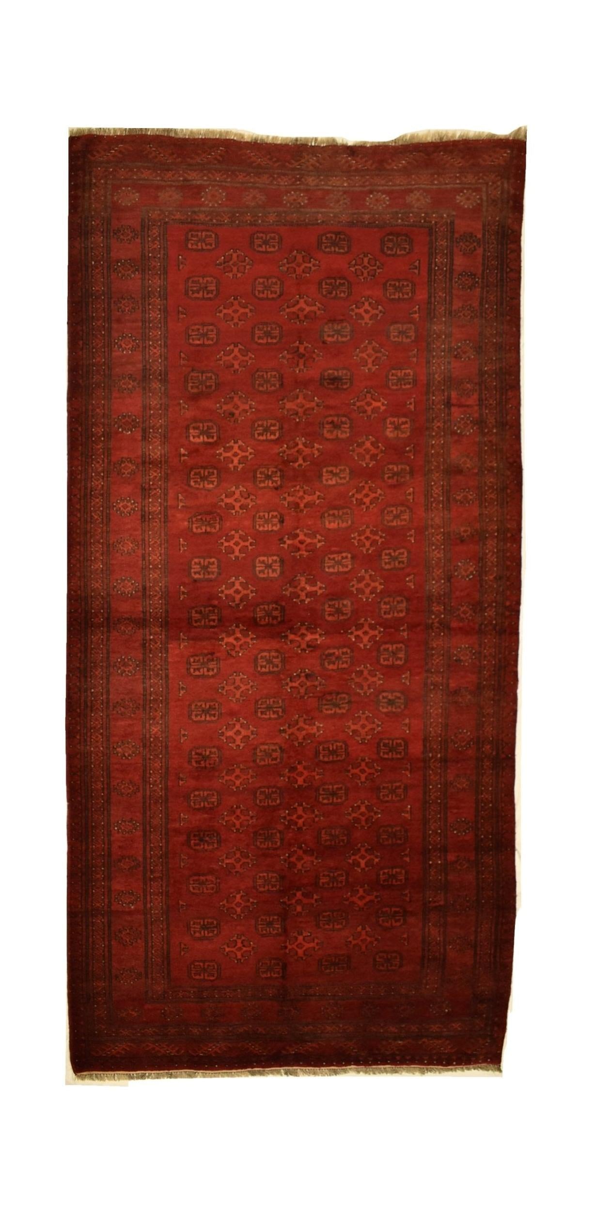 A vintage handmade Afghan Turkmen rug featuring a deep red field with repeating geometric motifs.