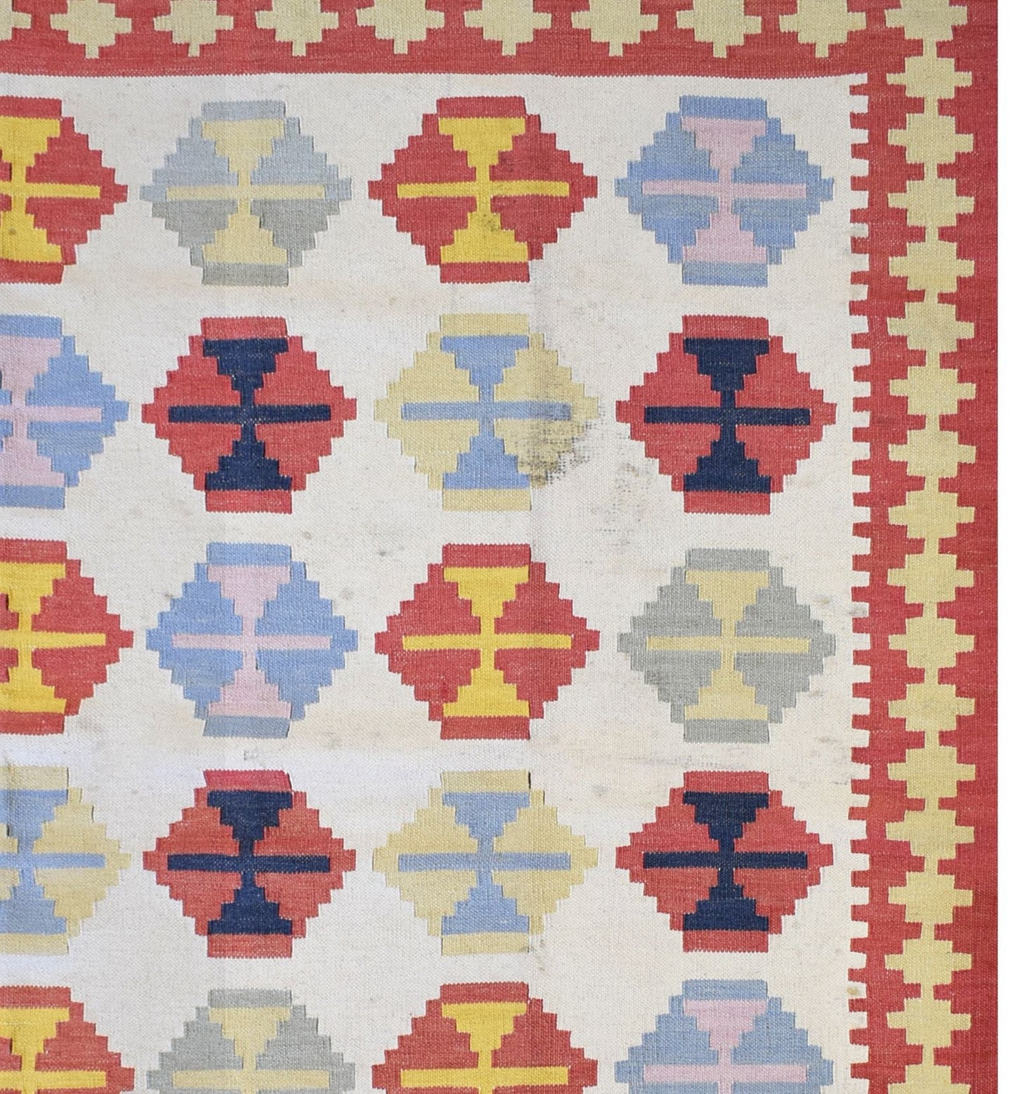 Handmade Turkish wool and cotton kilim rug featuring a repeating geometric pattern in red and blue.
