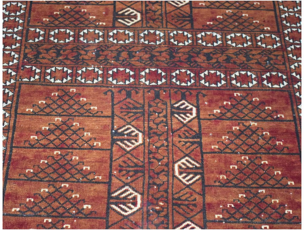 A vintage handwoven Afghan Turkmen rug featuring geometric patterns in shades of red and black.