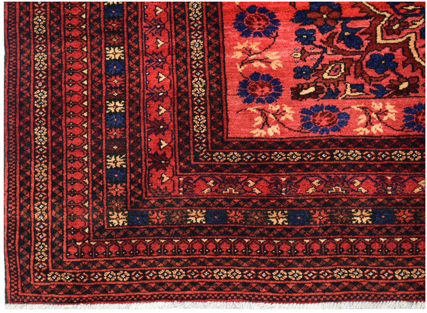 A vintage handwoven Afghan Baluch rug featuring a red field with blue floral motifs and borders.