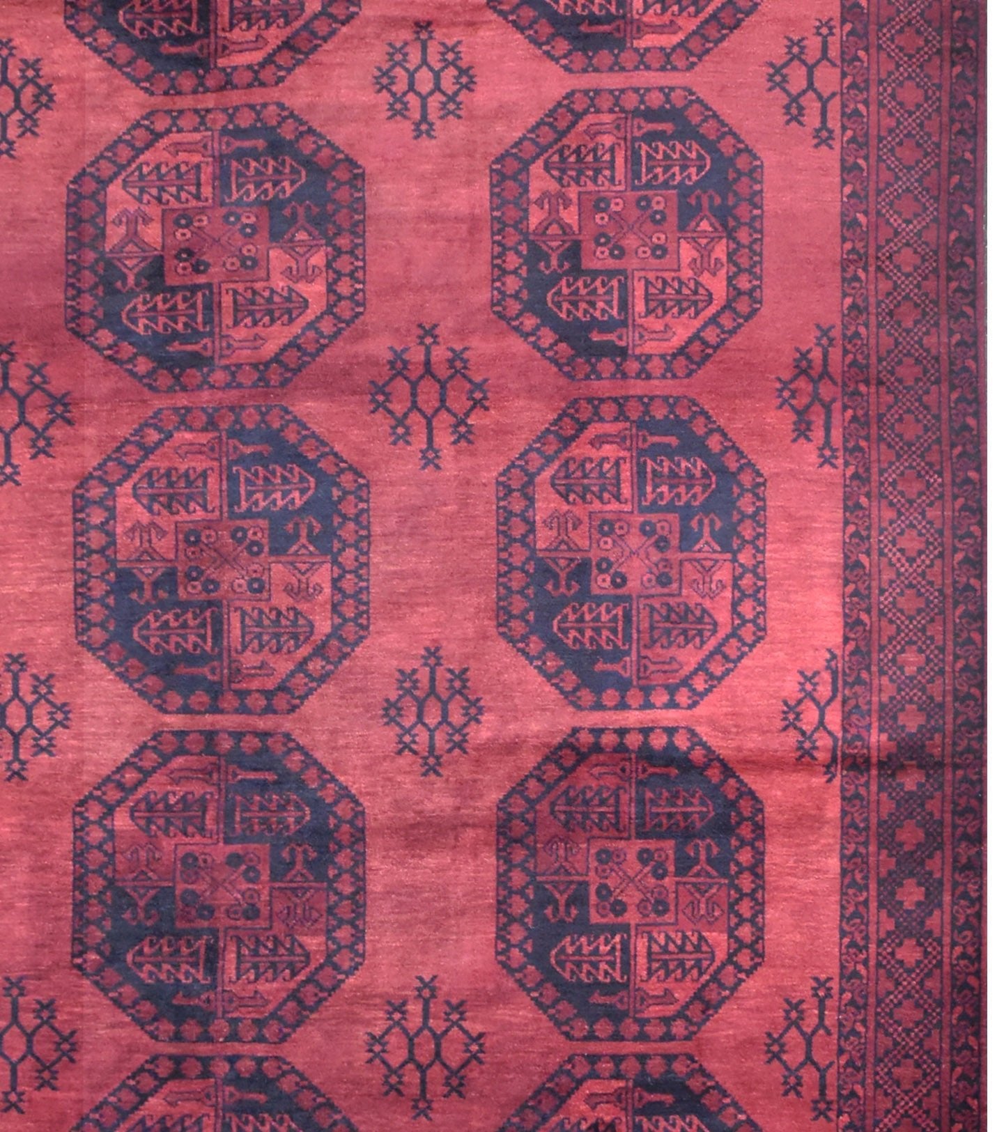 A vintage handmade Afghan Turkmen rug featuring repeating dark octagonal motifs on a red field.