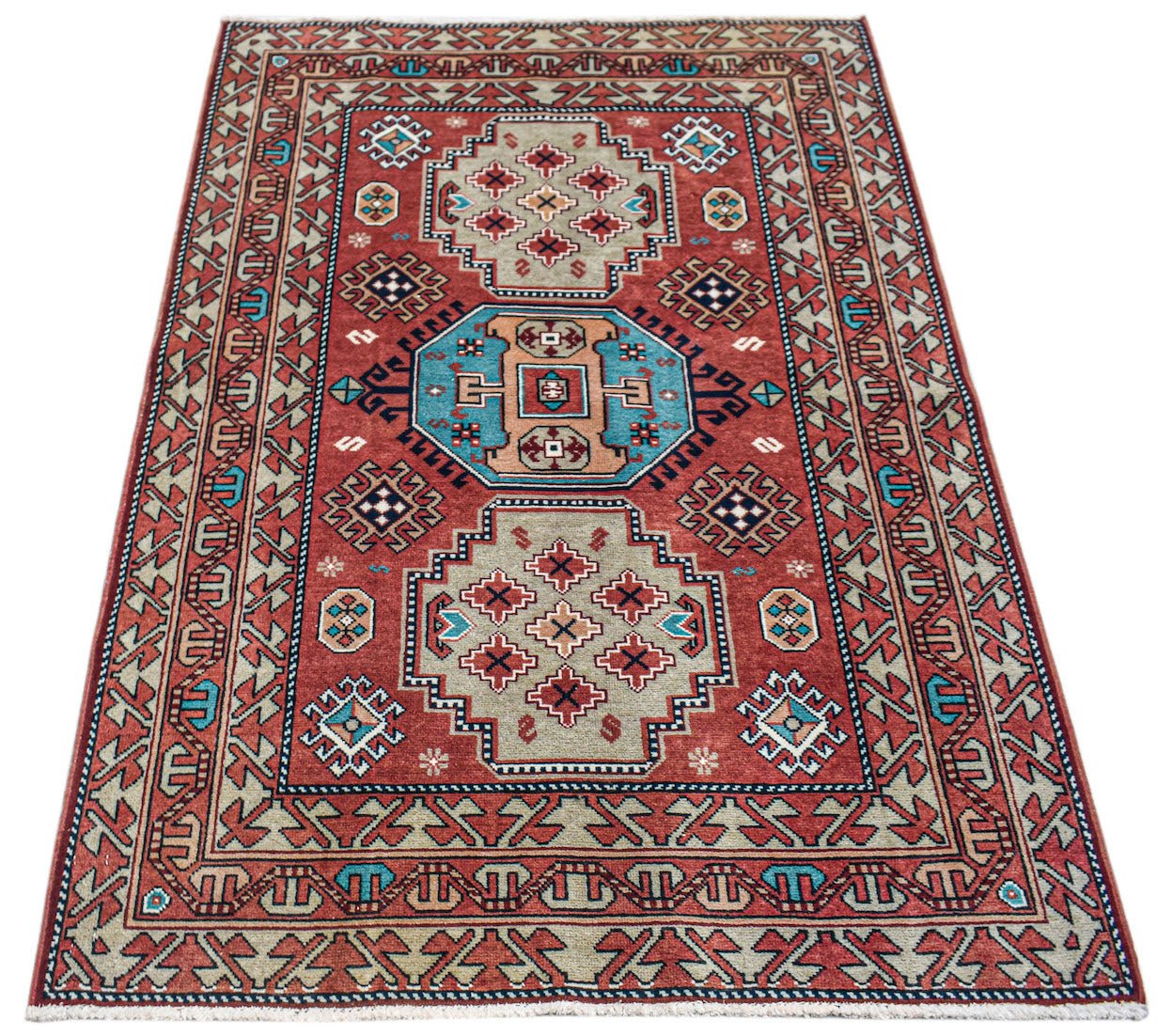 A handwoven vintage Caucasian rug featuring geometric patterns in red, blue, and beige tones.