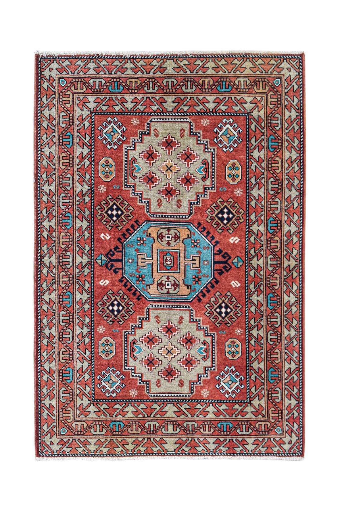 A handwoven vintage Caucasian rug featuring geometric patterns in red, blue, and beige tones.