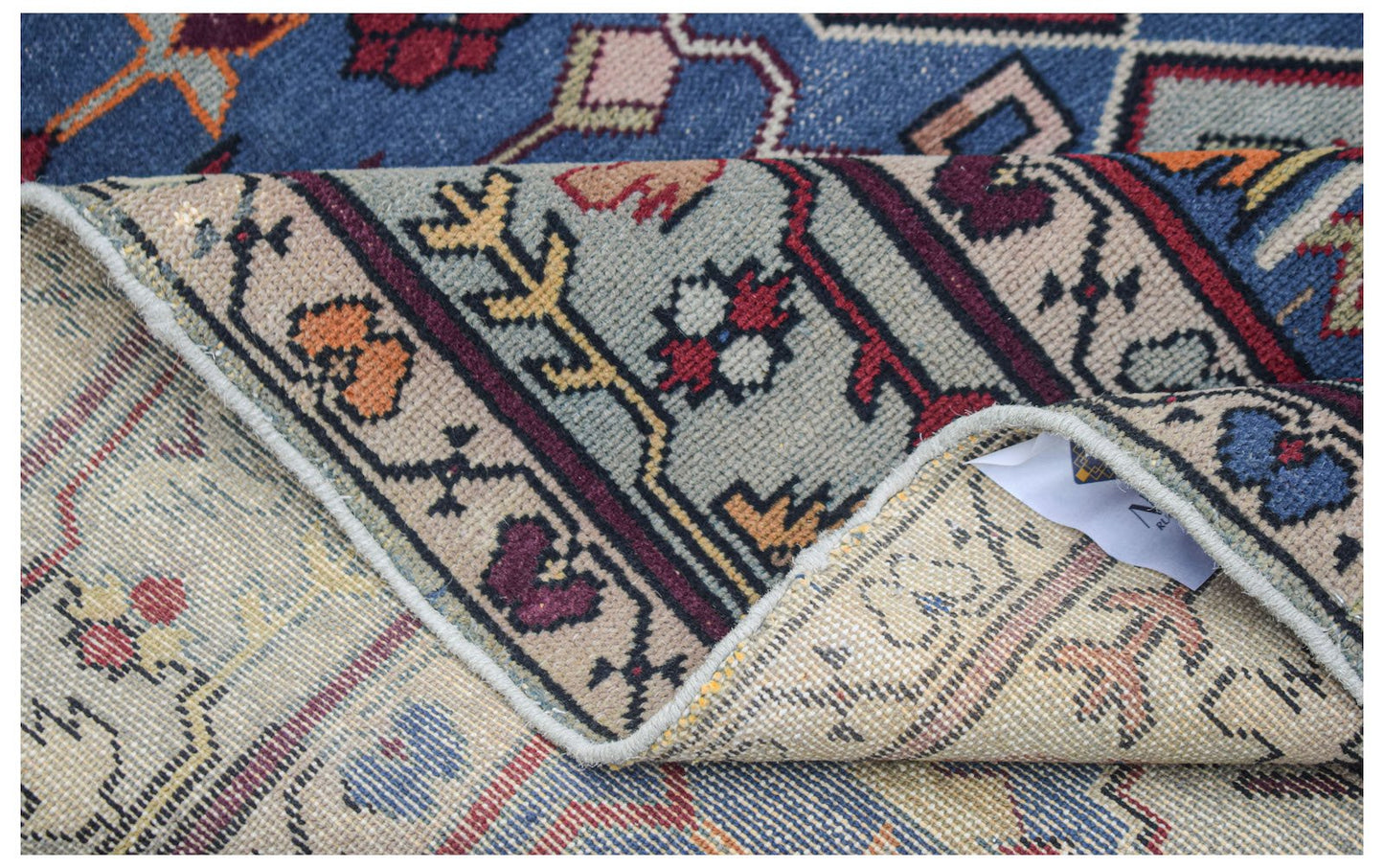 A vintage handwoven Caucasian wool rug with a blue and beige geometric pattern.